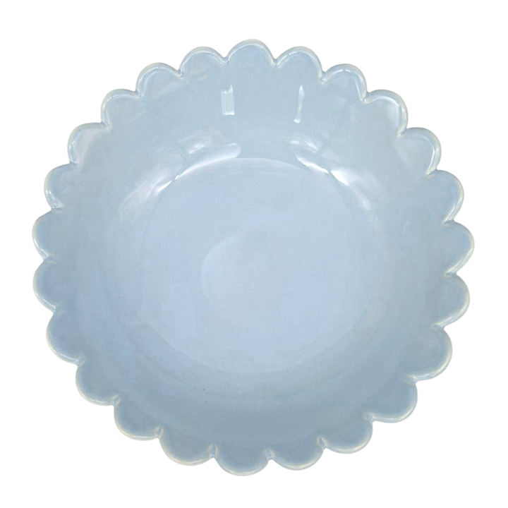 A scalloped-edge ceramic plate in a light blue glaze, photographed from directly above on a white background.