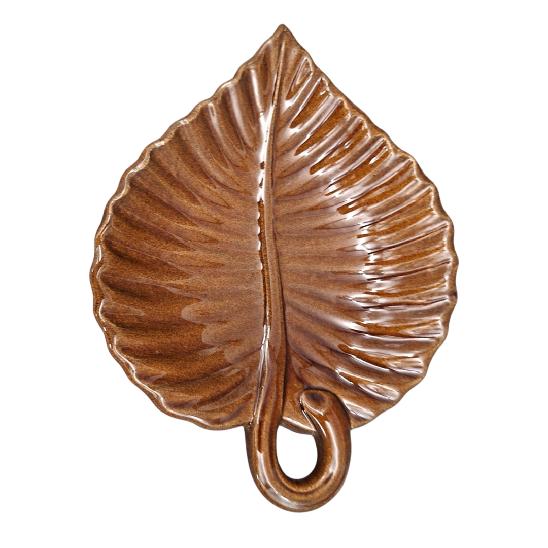 A glossy brown ribbed ceramic leaf-shaped plate with a curved rounded handle on a white background.