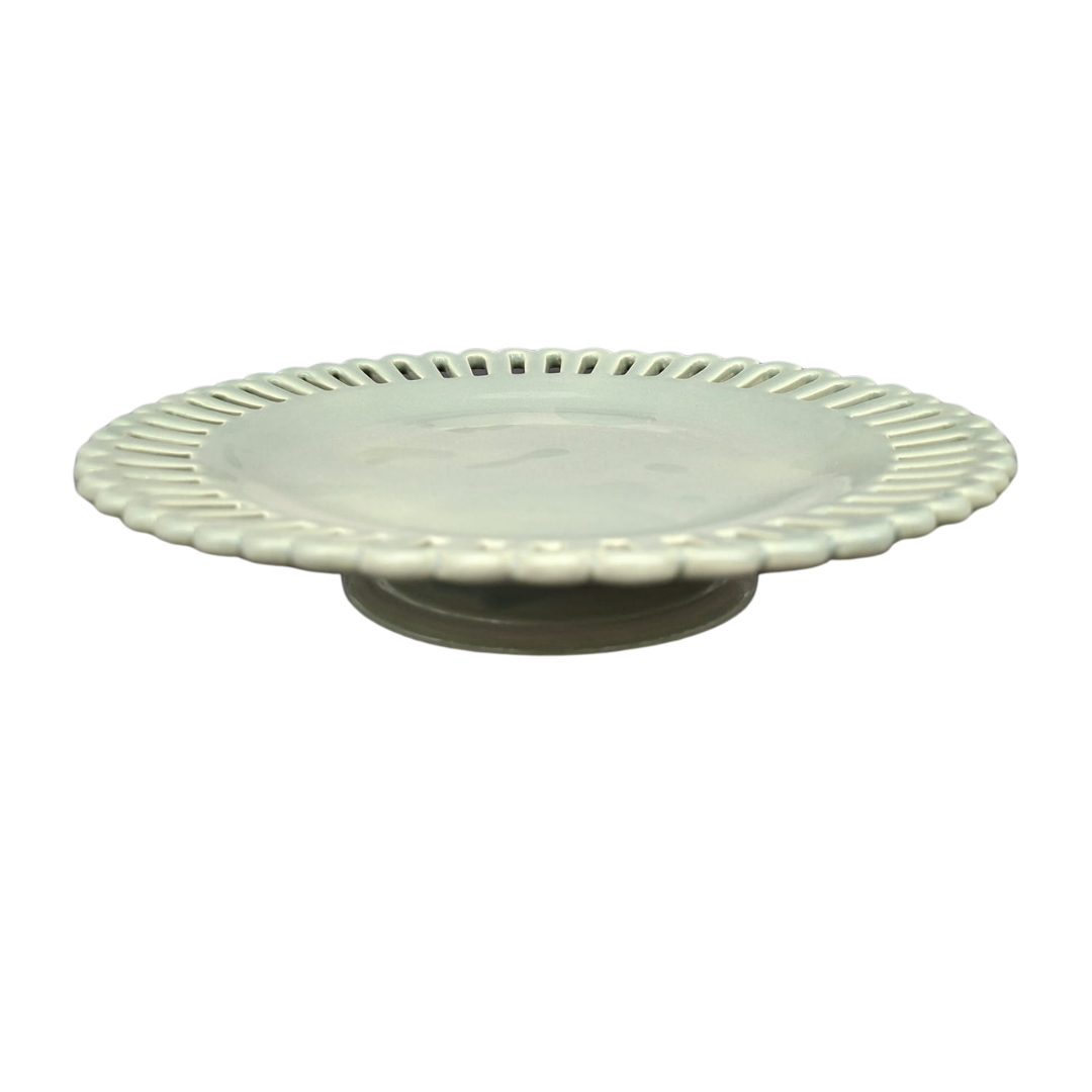 A sage green glaze ceramic pedestal plate with a scalloped, fluted rim and openwork edge, shown on a plain white background.