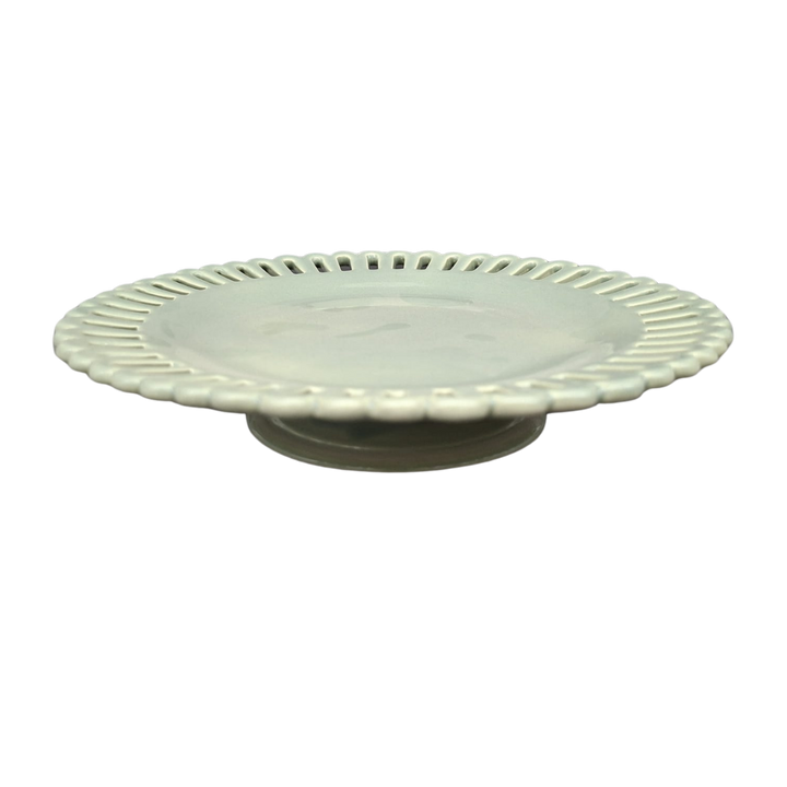 A sage green glaze ceramic pedestal plate with a scalloped, fluted rim and openwork edge, shown on a plain white background.