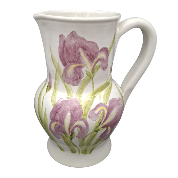 A white ceramic pitcher decorated with painted purple irises and green leaves, shown against a plain white background.