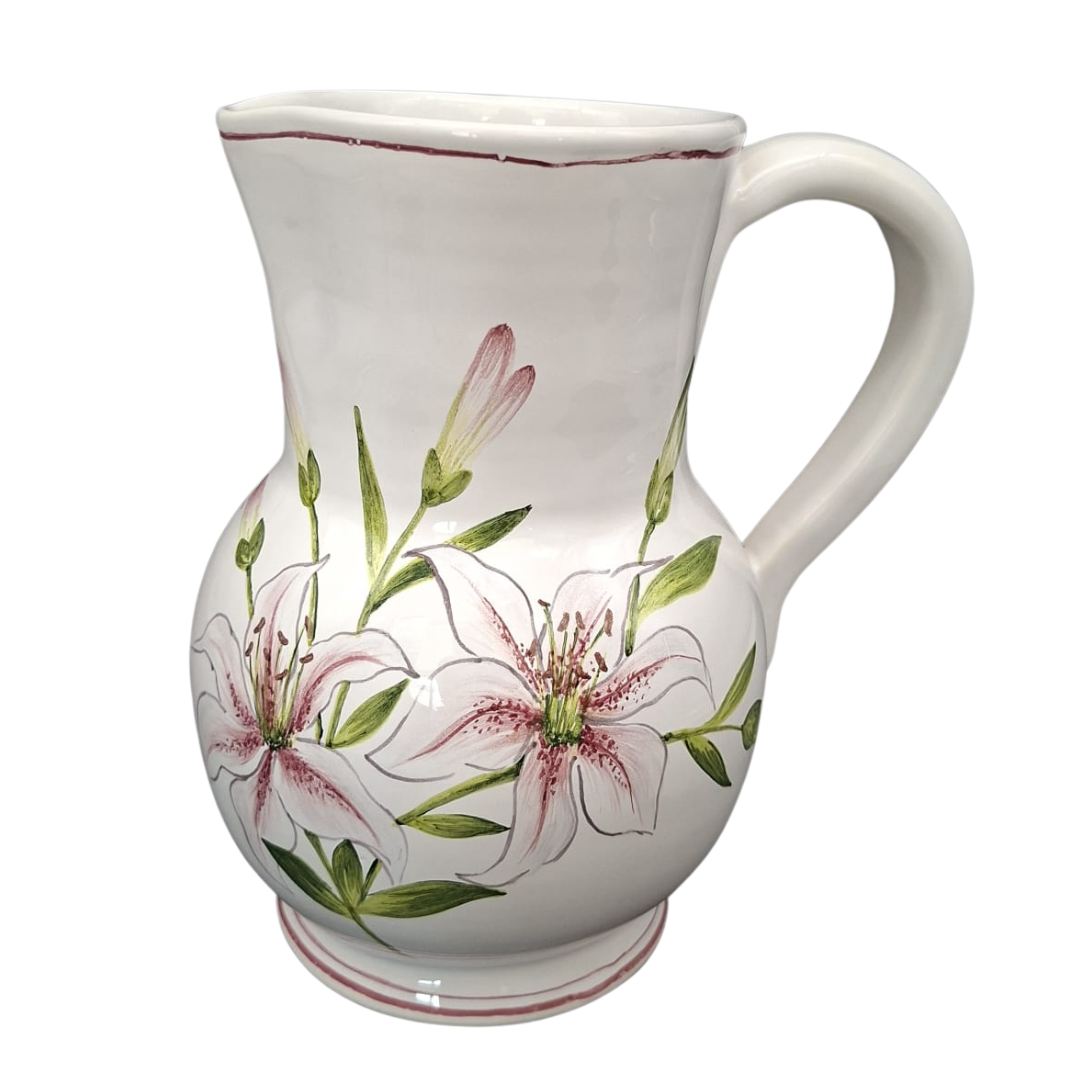 A white ceramic pitcher decorated with pink and white lily flowers and green leaves, shown against a plain white background.