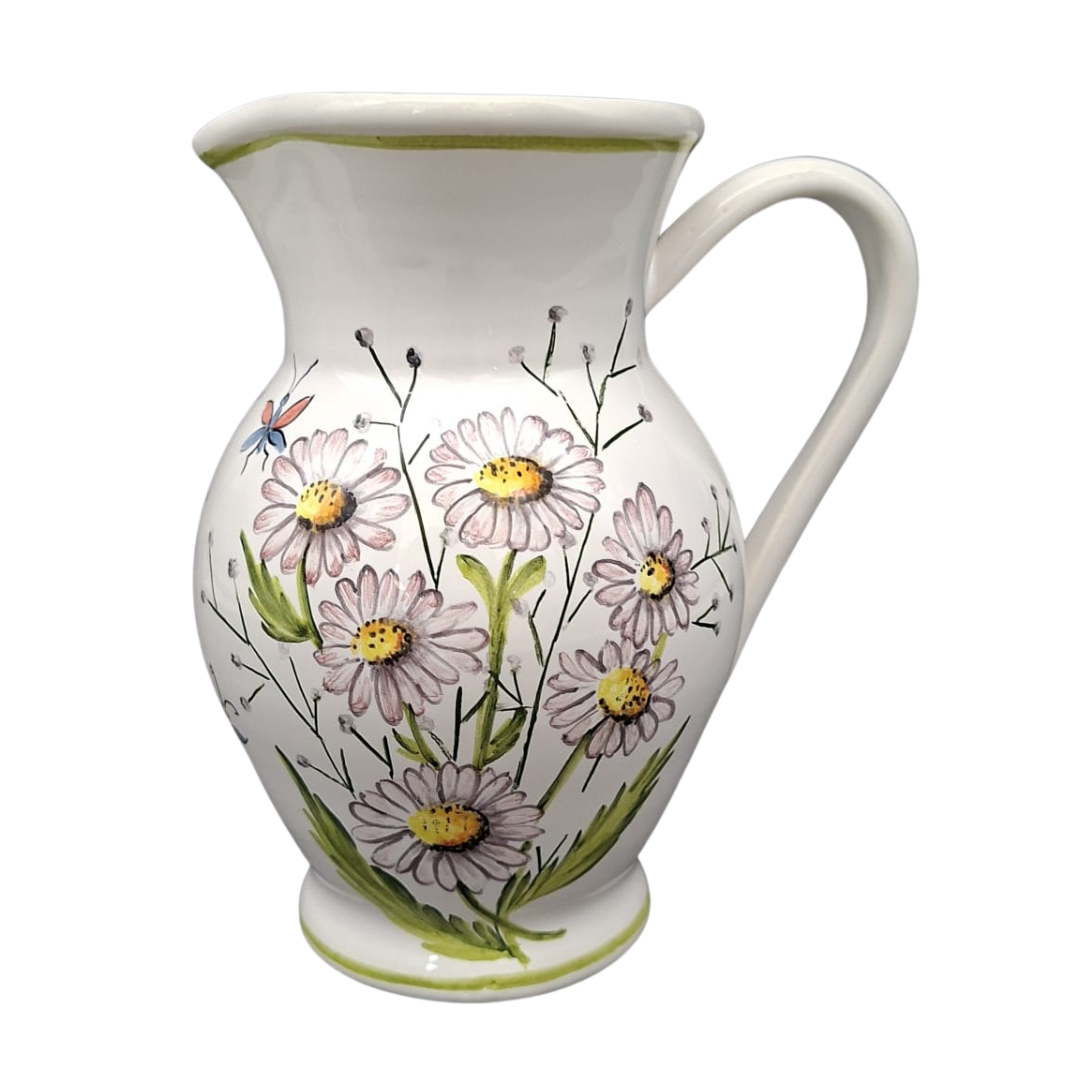 A white ceramic pitcher decorated with a hand-painted floral design of daisies in pink, yellow, and green, with a small blue dragonfly accent.